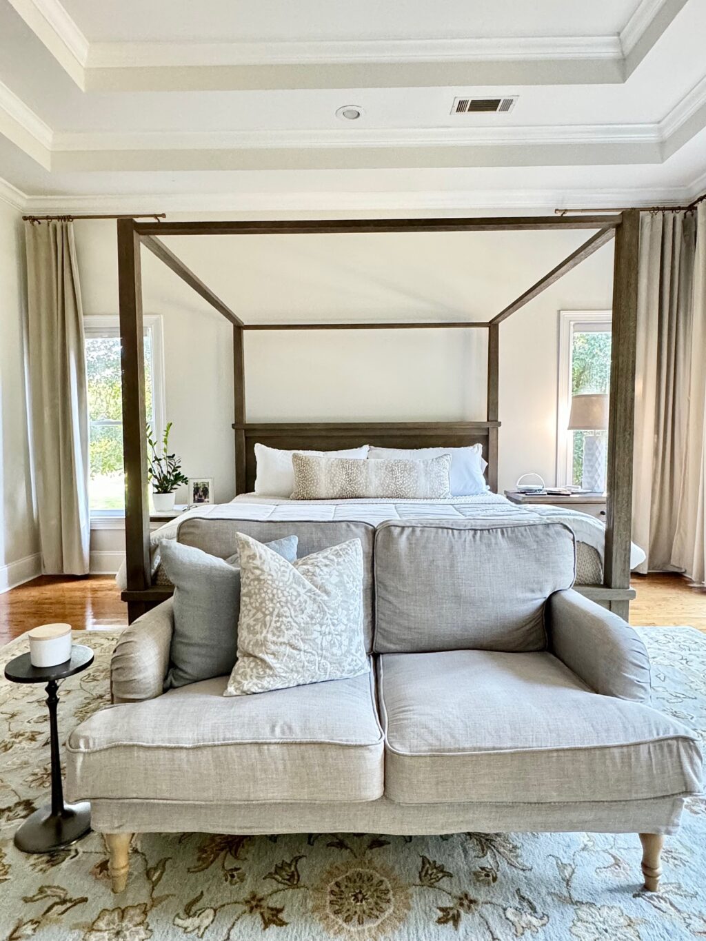 small loveseat in front of canopy bed