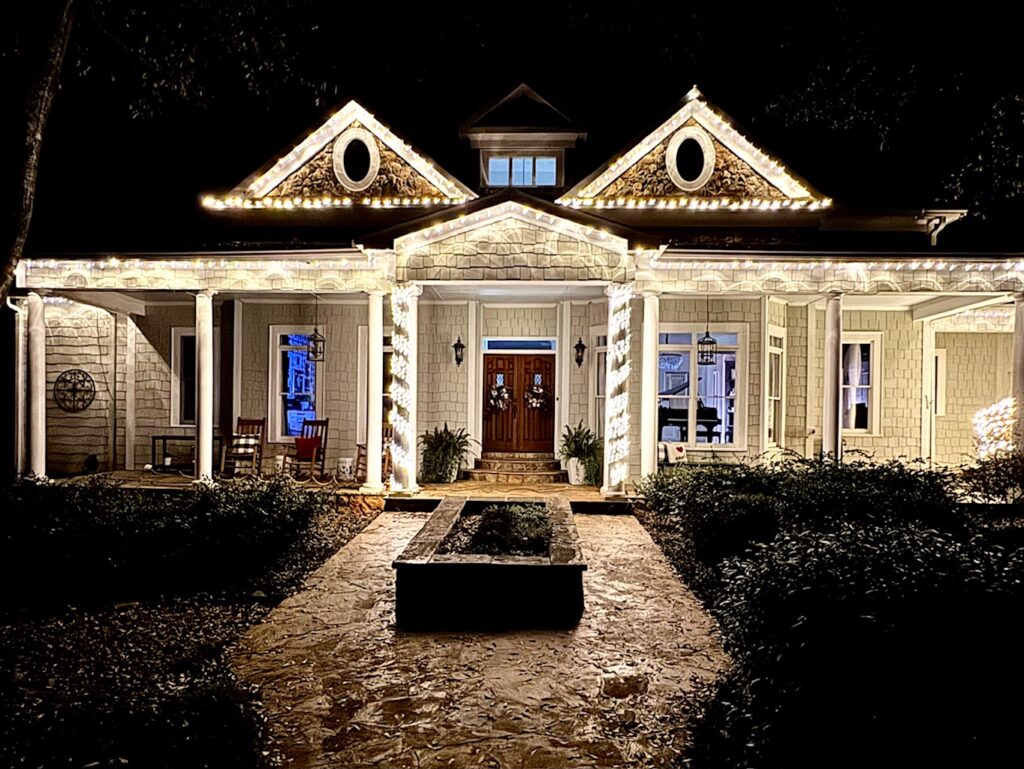 dark sky behind house with holiday light on roof and front porch